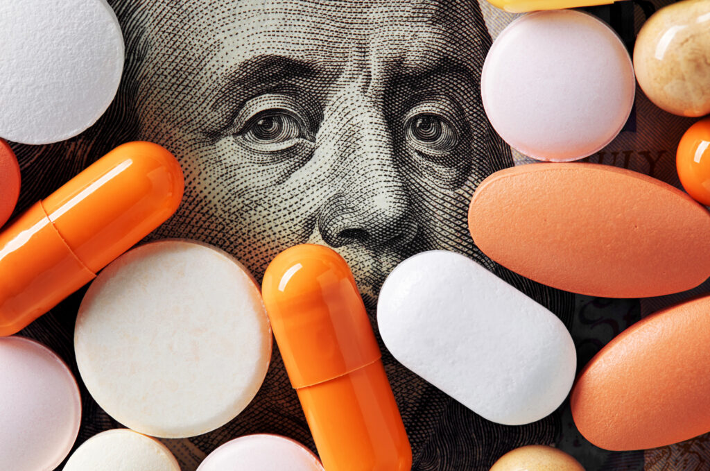 healthcare cost concept. Colorful medical pills cover Benjamin Franklin's face on one hundred american dollar bill.